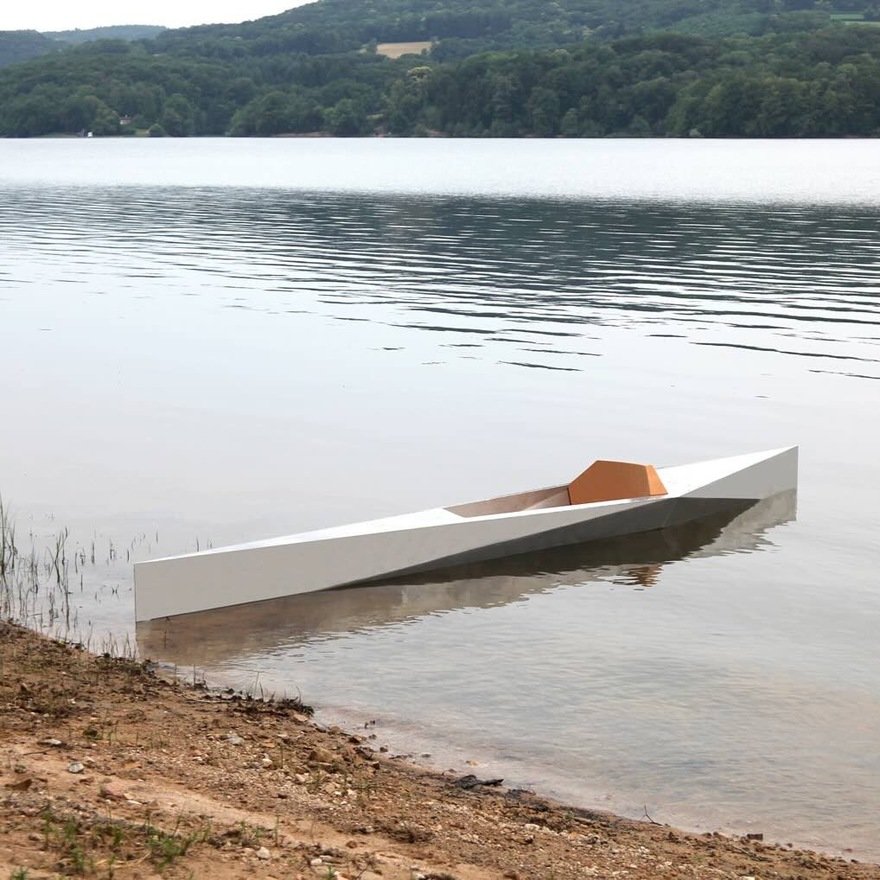 A sleek white and orange boat partially submerged in calm water with a wooded landscape in the background.