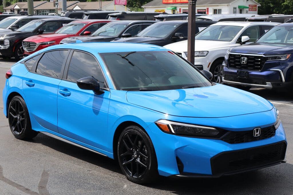 A bright blue car parked in a dealership, surrounded by various vehicles.