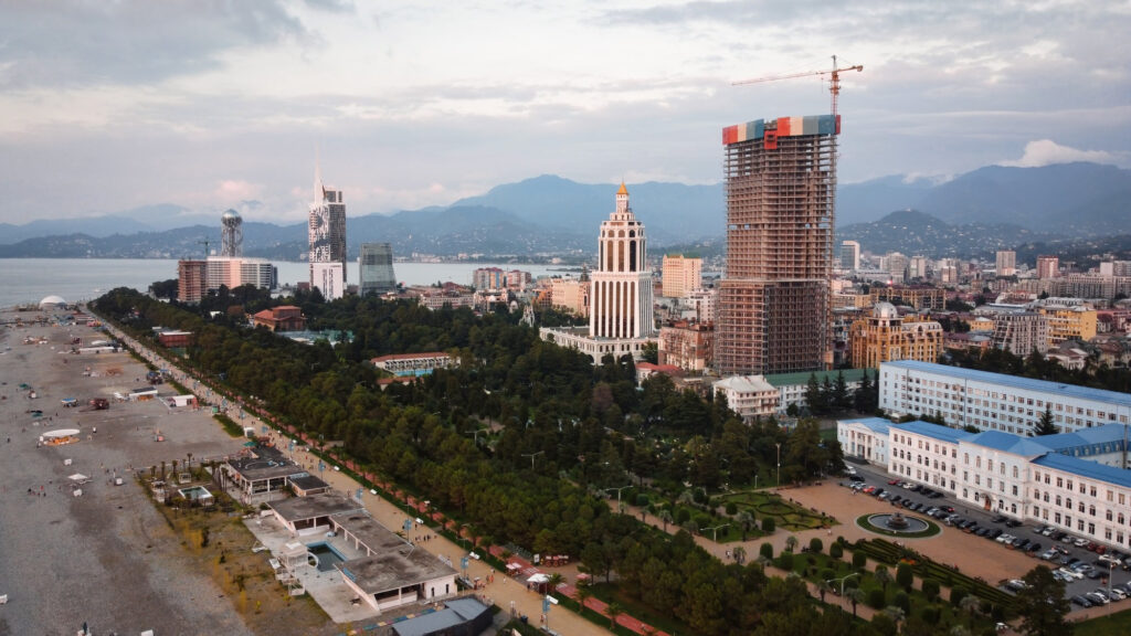 Aerial view of a city with modern buildings and a beach shoreline at sunset